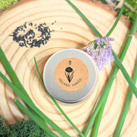 Organic chives seeds tin on wooden slice with purple chive blossoms