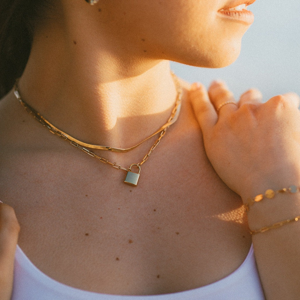 Gold herringbone necklace layered with a fine chain and small pendant
