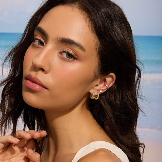 Gold sculpted hoop earrings on ear, ridged curved hoops