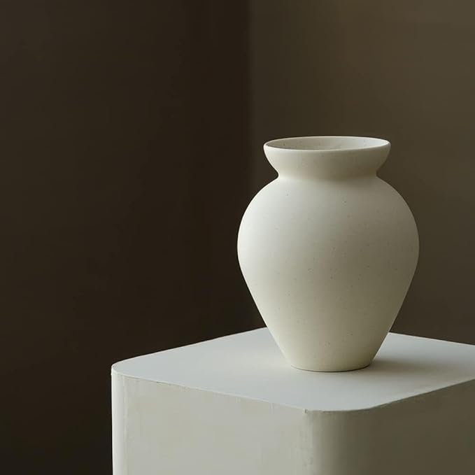 Cream ceramic milk can vase with matte speckled texture and flared top on a pedestal.