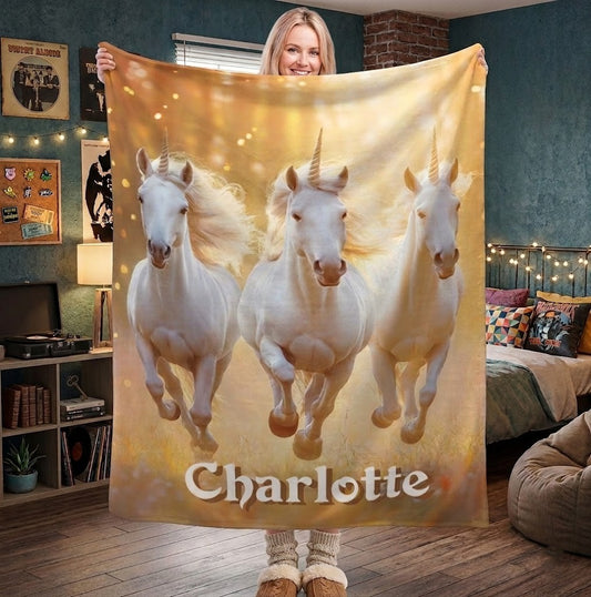 Unicorn name blanket held up with three white horses and gold sparkle, name Charlotte