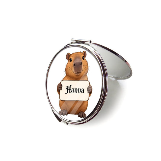 Open silver compact mirror showing capybara artwork on the lid