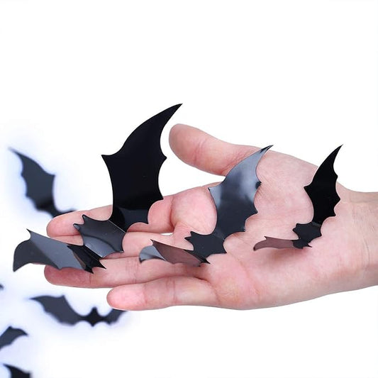 Black 3D bat wall decals held in a hand, layered cutout bat shapes for Halloween