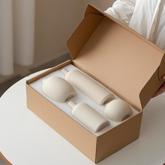 Four beige matte ceramic vases packed in a cardboard box, ready for unboxing