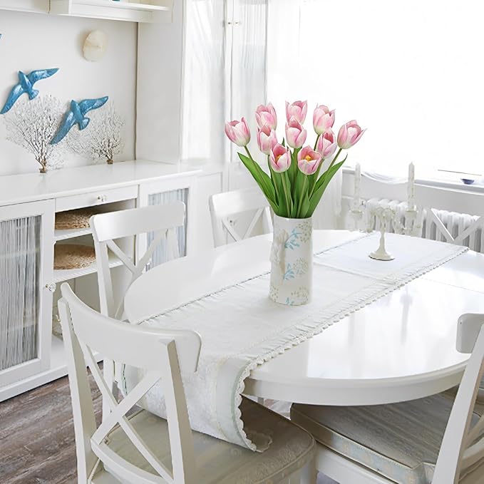 Pink faux tulip stems in a clear vase on a white dining table