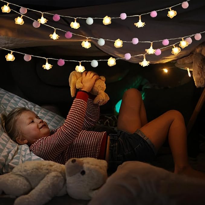 Warm rose LED string lights with pink and white pom-pom balls across a tent canopy