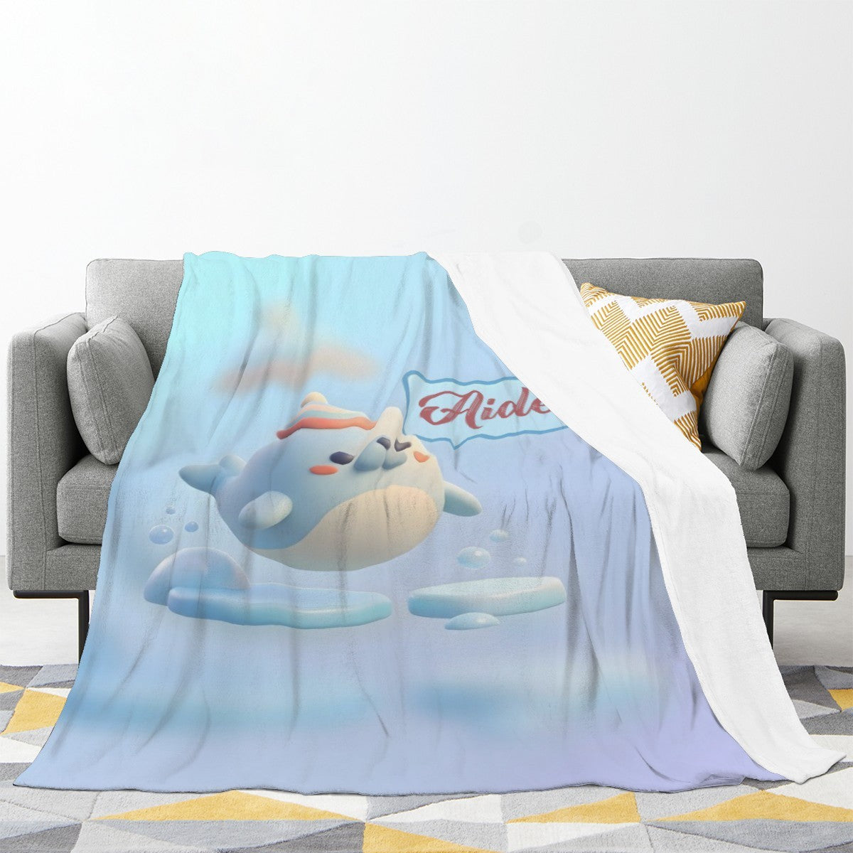 Light blue plush blanket draped over a sofa with seal character print