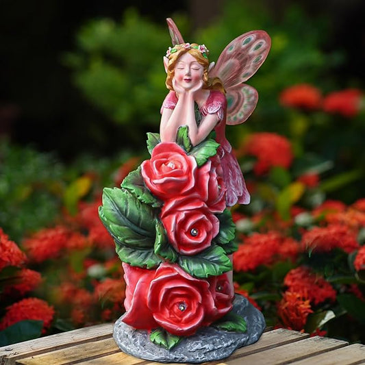 Solar fairy garden statue with a pink dress, red rose cluster, butterfly wings, on a stone base