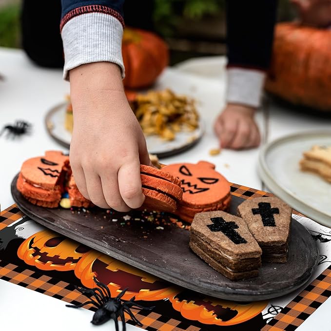 Hand setting treats on a black-and-orange plaid Halloween paper placemat with pumpkin art