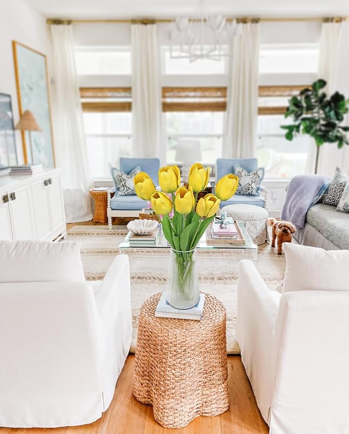 Yellow faux tulip stems in a clear vase on a woven round table cover