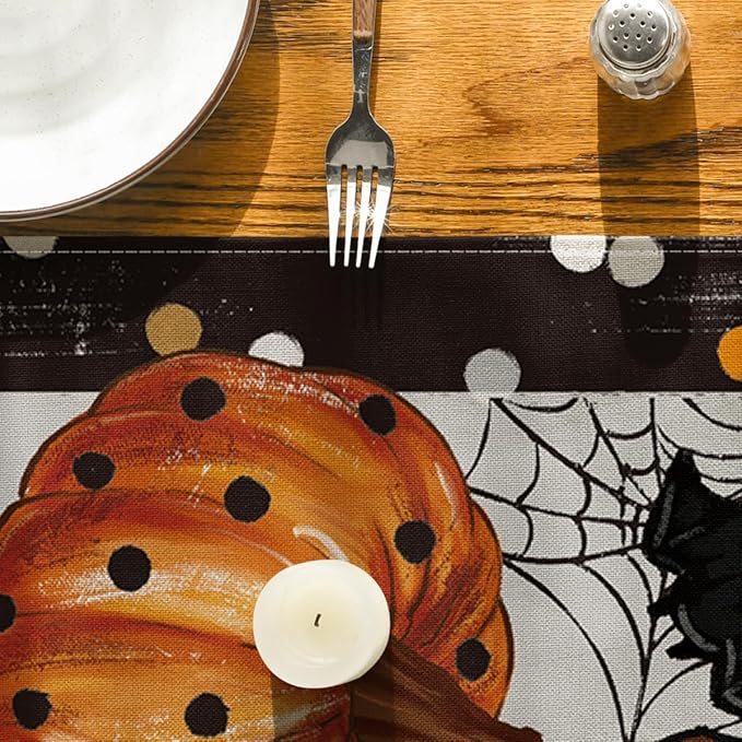 Close-up Halloween table runner corner with orange pumpkins, white ghosts, and spiderweb