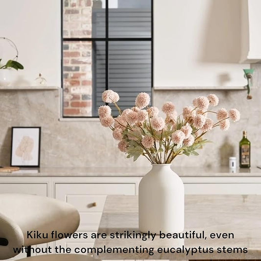 Beige faux pom-pom blooms and gold eucalyptus stems in a vase