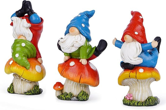 Three mushroom gnome statues with blue, green, and red caps, arms out and white beards