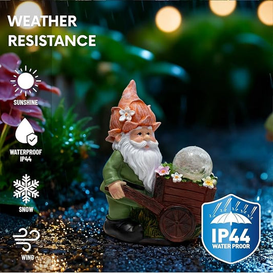 Green garden gnome statue with crackle globe light in dark red wheelbarrow outdoors