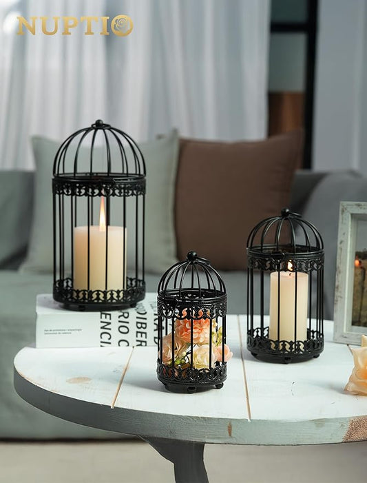 Black birdcage tealight candle holder on a table with warm candle flames