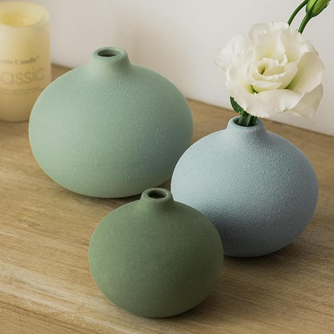 Three mini ceramic bud vases on wood in mint, sage green, and light blue with flowers