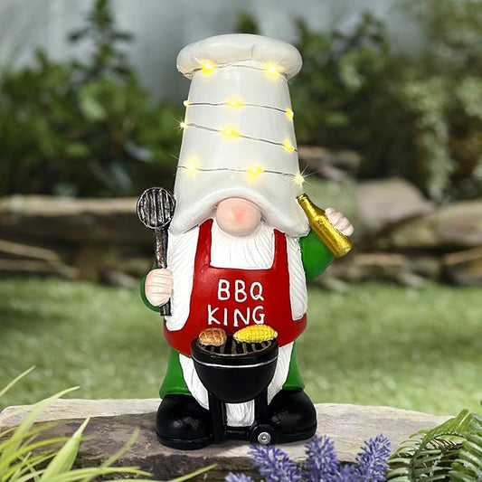 BBQ King garden gnome holding a bottle, with lit solar string lights and grill