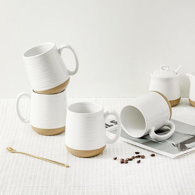 White ceramic coffee mugs with handles and gold base ring on a tabletop