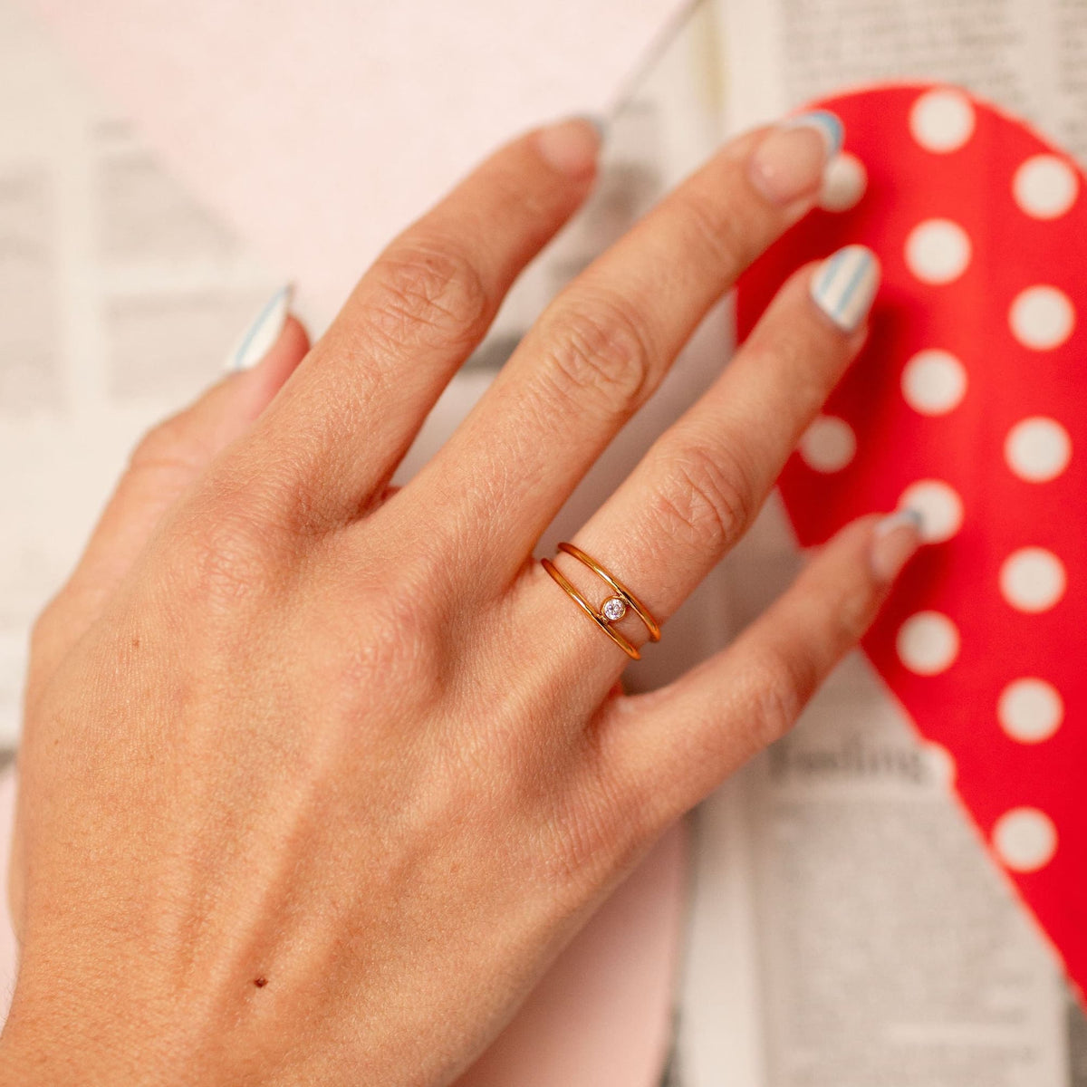 Rose gold double-band ring with a round cubic zirconia stone, worn on a hand