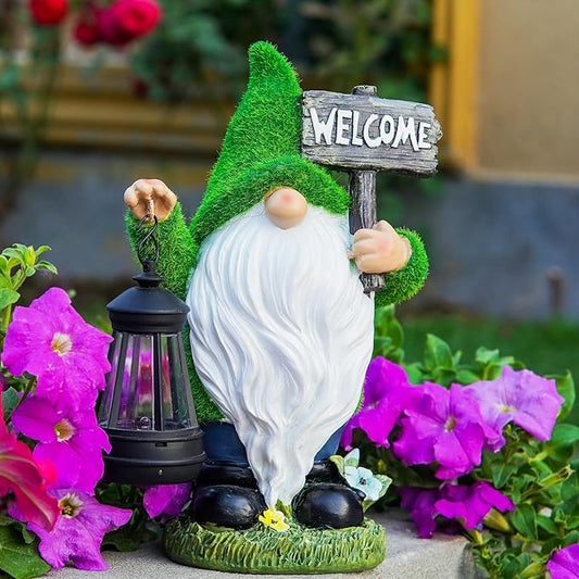 Green garden gnome with white beard holding a black solar lantern and rustic “WELCOME” sign