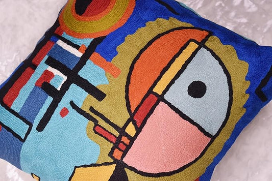 Close-up of blue abstract pillow cover with orange, yellow and black face shapes
