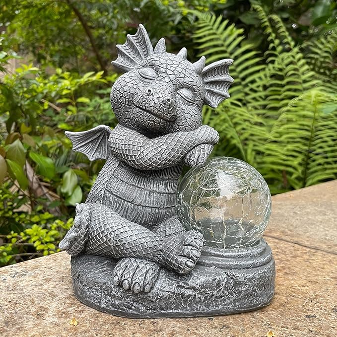 Gray dragon resin figurine holding a glowing glass orb, resting on a textured base