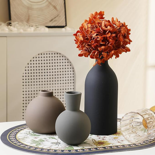 Set of 3 ceramic vases with dried stems; black tall bottle and beige rounded vase shapes.