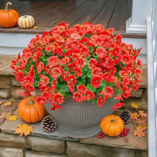 Faux orange daisy-style flowers with green eucalyptus-style leaves in a ribbed planter