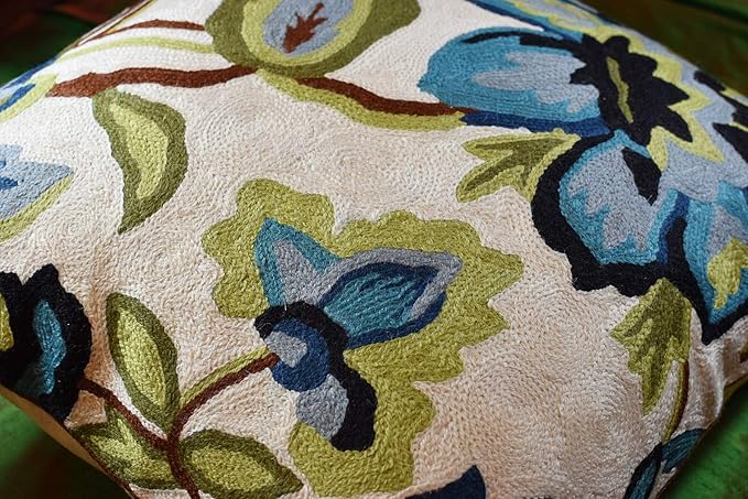 Close-up floral pillow cover in cream with blue and green embroidered flowers and leaves