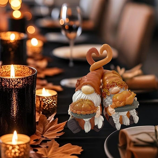 Two resin gnome figurines in fall colors holding turkey and pumpkin pie