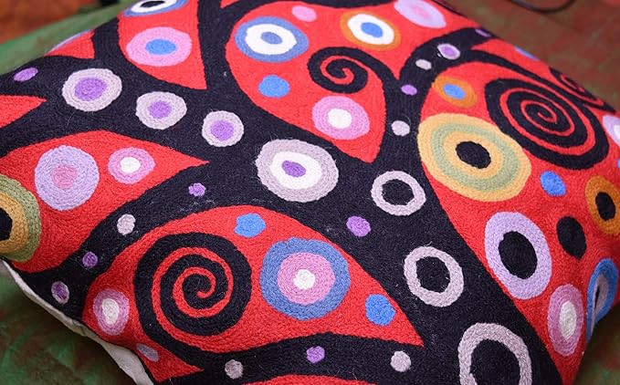 Red and black pillow cover with multicolor circular spirals and ring motifs.
