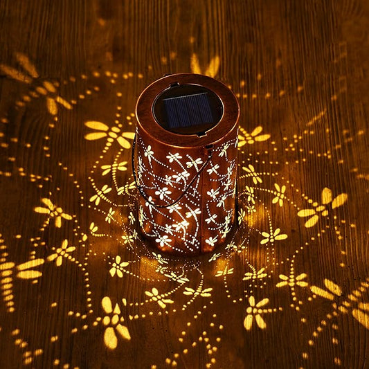 Brown solar lantern with white dragonfly and floral design, emitting warm glowing light
