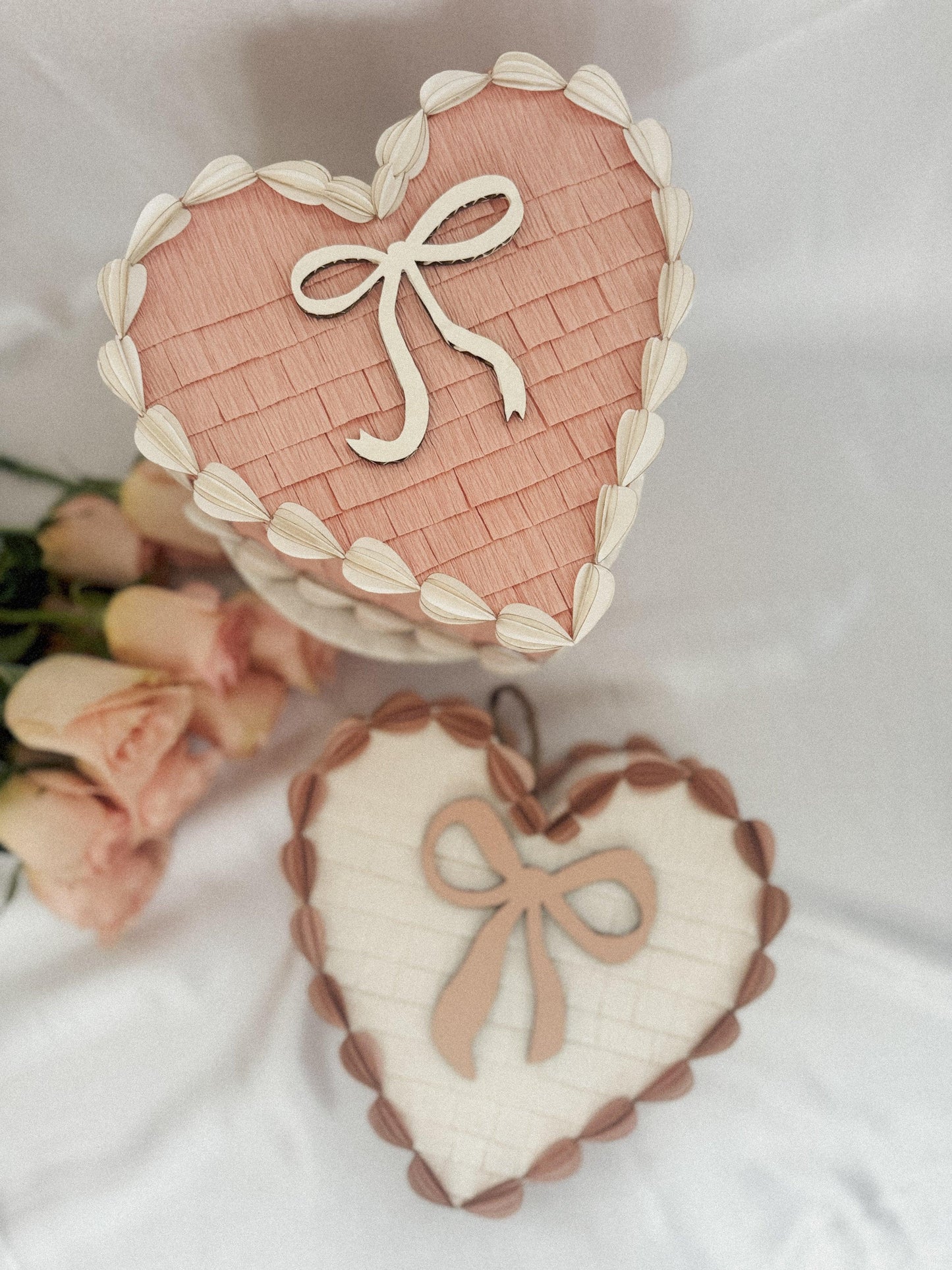 Corazones piñata San Valentín: uno rosa con lazo blanco y otro crema con lazo rosa