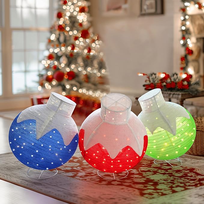 Three lit pop-up Christmas ball ornaments in red, blue and green on a wooden table
