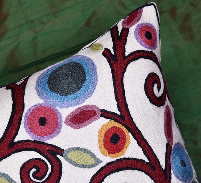 White pillow cover close-up of leaves, dots, and spiral accents in blue and red
