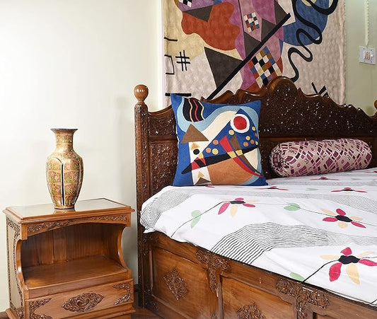 Blue abstract decorative pillow cover with colorful geometric shapes on a bed