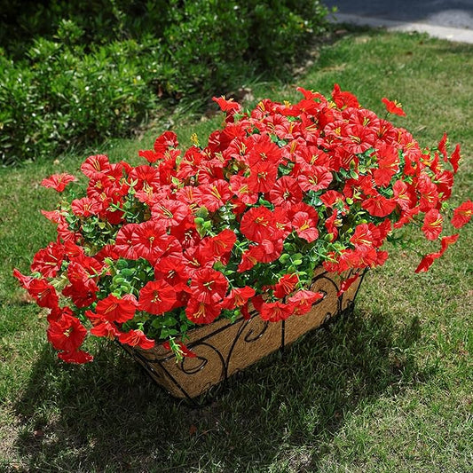 Red faux morning glory flowers with green leaves on a black wire planter basket