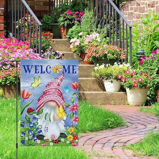 Spring gnome garden flag on an outdoor pole, WELCOME text with butterflies and tulips