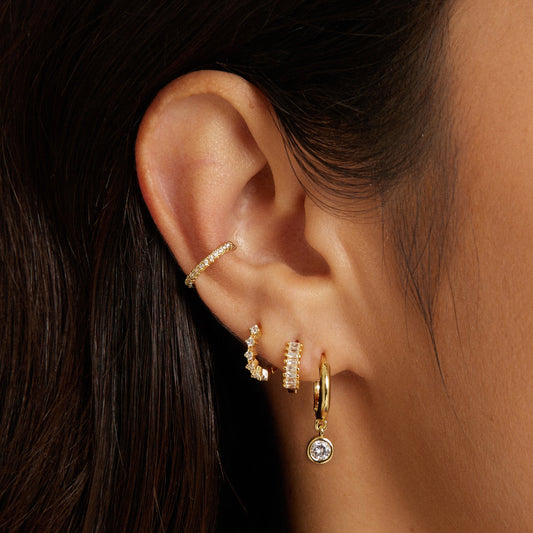Gold huggie hoop earrings featuring clustered rhinestones on the hoop