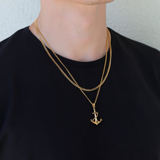 Gold anchor pendant on Cuban link chain necklace set, close-up on layered pendants