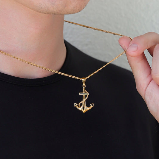 Gold anchor pendant necklace worn with a second chain, shown near collarbone