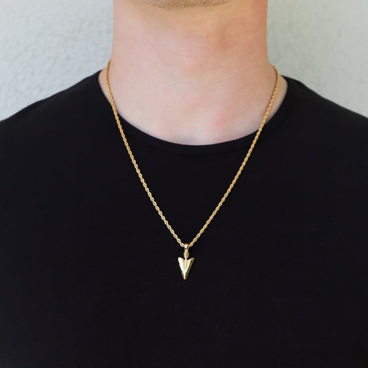 Gold arrow pendant necklace with twisted chain, worn on a dark crew-neck shirt.
