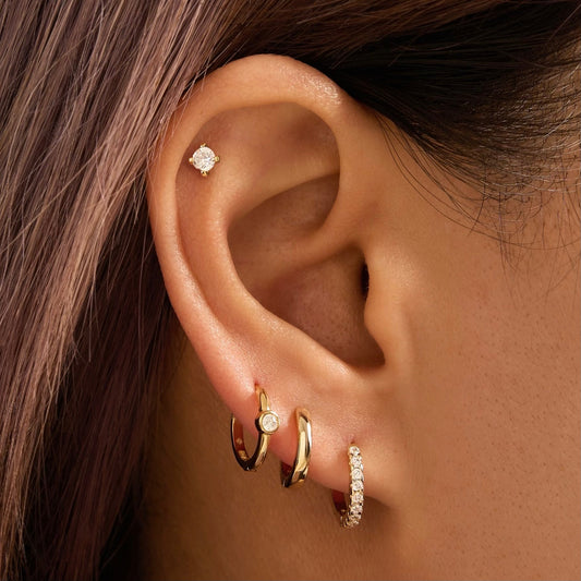 Gold hoop earring with round bezel-set stone, on ear