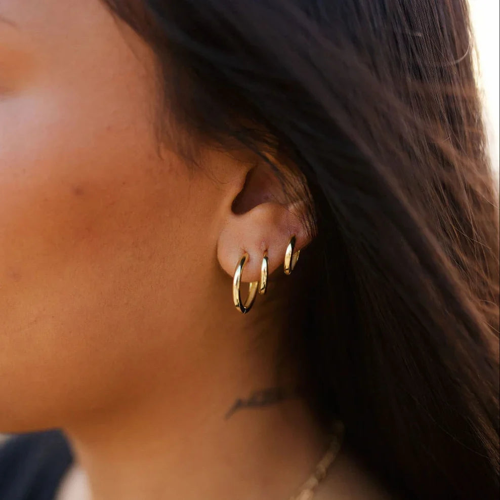 Three gold hoop earrings worn in one ear