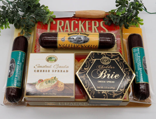 Wooden cutting board gift set arranged with crackers, cheese spreads, and sausage links