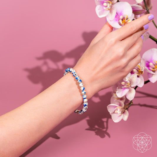 Blue and white beaded stone bracelet on wrist, round beads with speckled texture