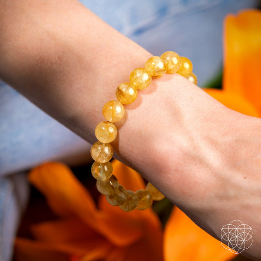 Golden healer quartz bracelet on wrist with amber-gold round beads
