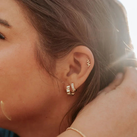 Gold leaf stud earring worn on the upper ear