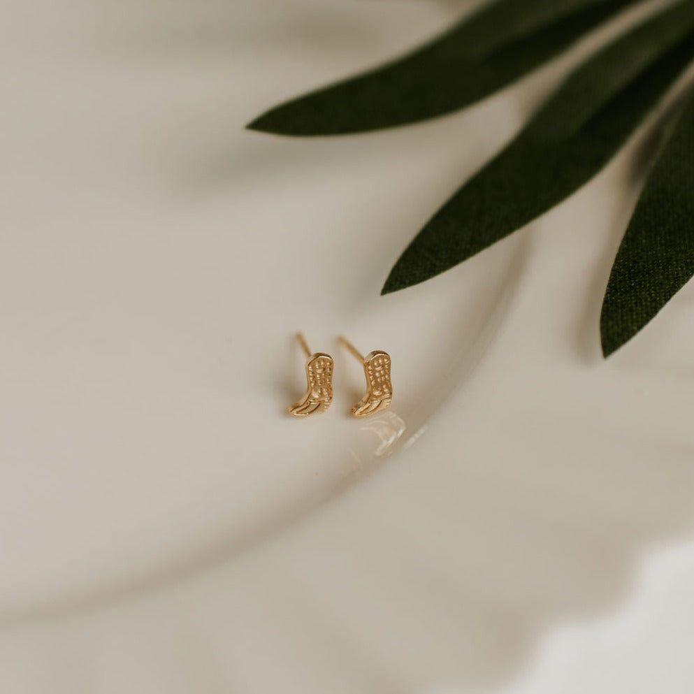 Pair of gold-tone cowboy boot stud earrings with visible posts