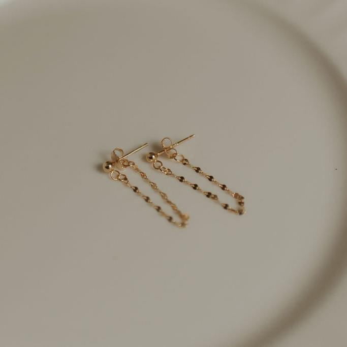 Close-up of paired gold vermeil chain huggie-style stud earrings